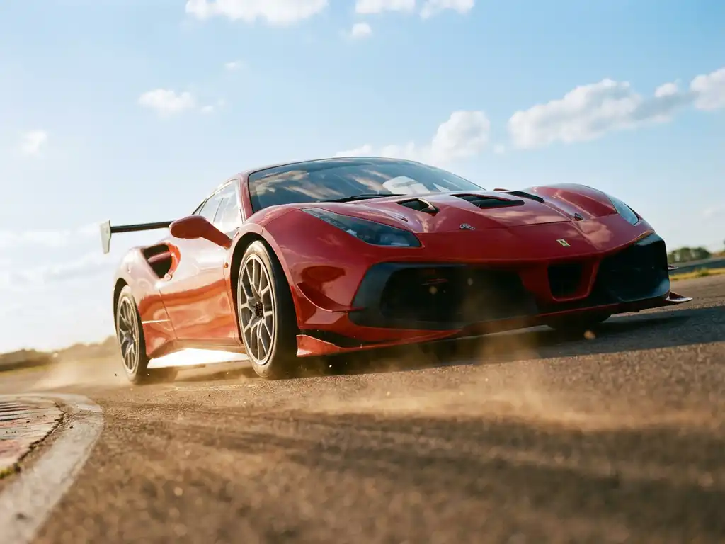 Ferrari 488 Challenge Rennauto in Rosso Corsa nimmt eine Kurve auf europäischer Rennstrecke im goldenen Nachmittagslicht.