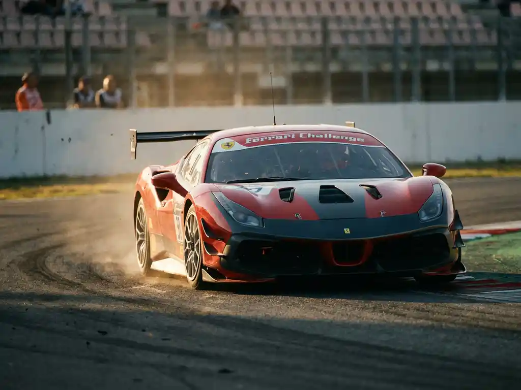Ferrari Challenge Rennauto in schneller Kurvenfahrt auf europäischer Rennstrecke, Reifen unter Last, Tribünen im Hintergrund unscharf.